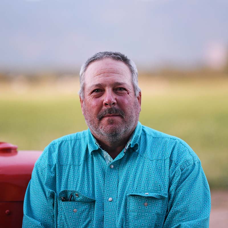 Man wearing a blue shirt standing in front of a blurred background
