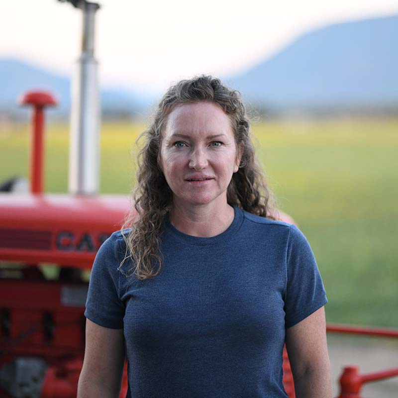 Woman standing in front of a red tractor with a blurred natural background