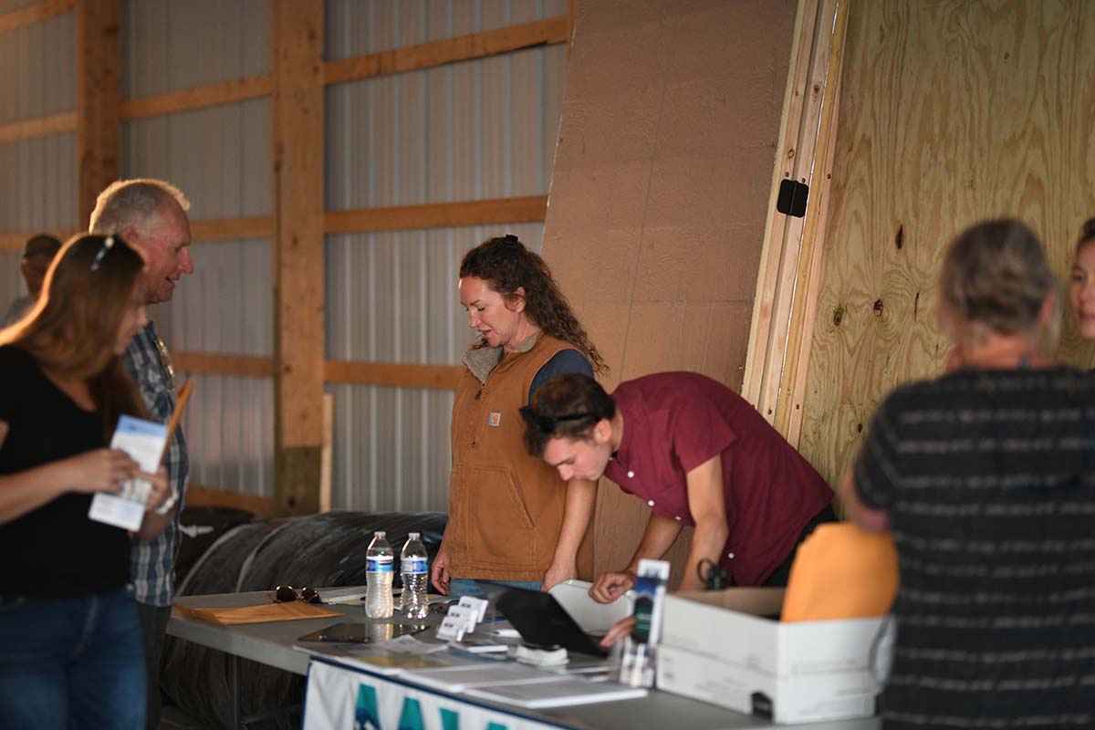 People gathered around a table with a laptop in a barn in Montana.