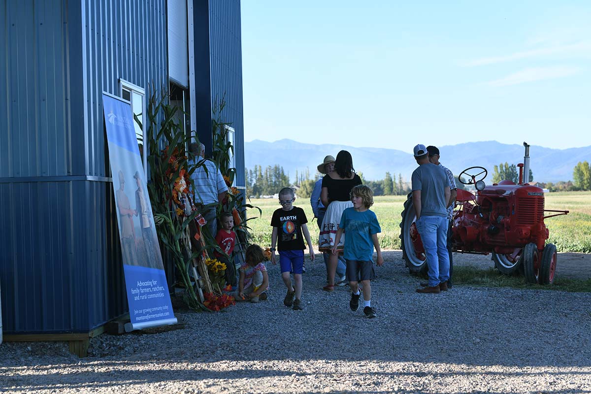 People standing near a red tractor and outside a barn in Montana.