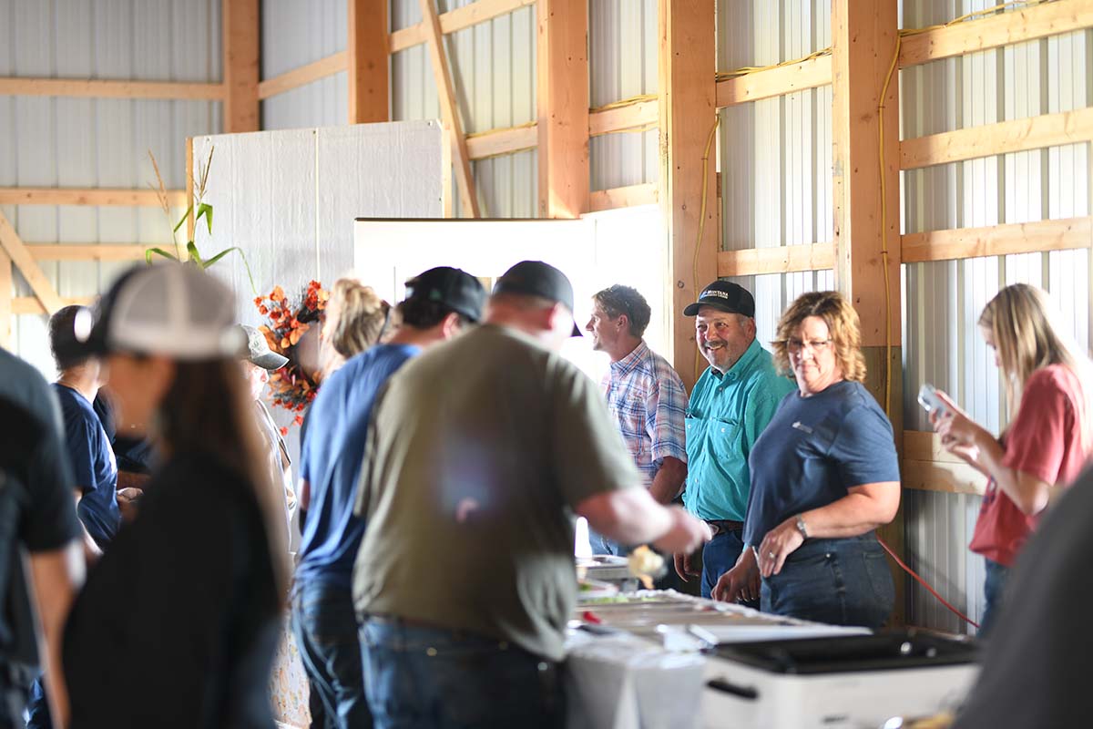 Group of people gathered around a table in a rustic barn.