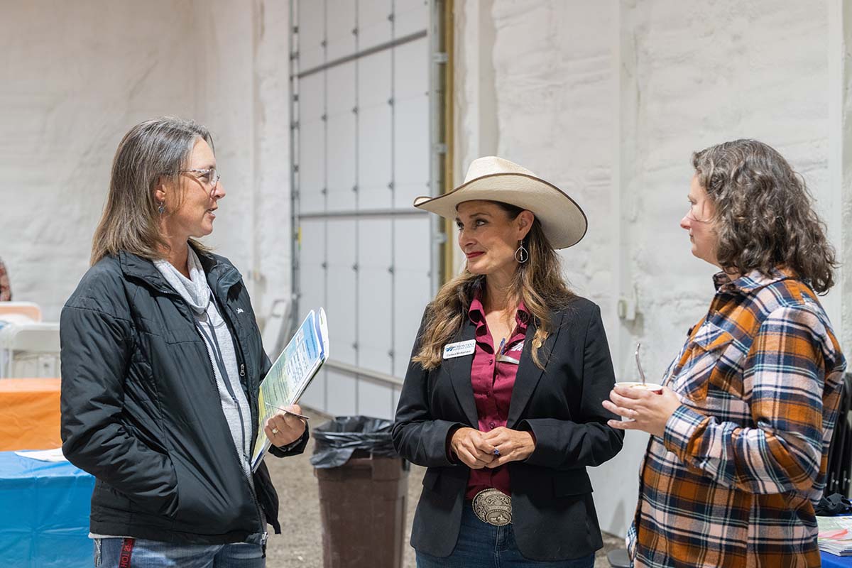 Three Montana farmers talking at a meat cooperative event.