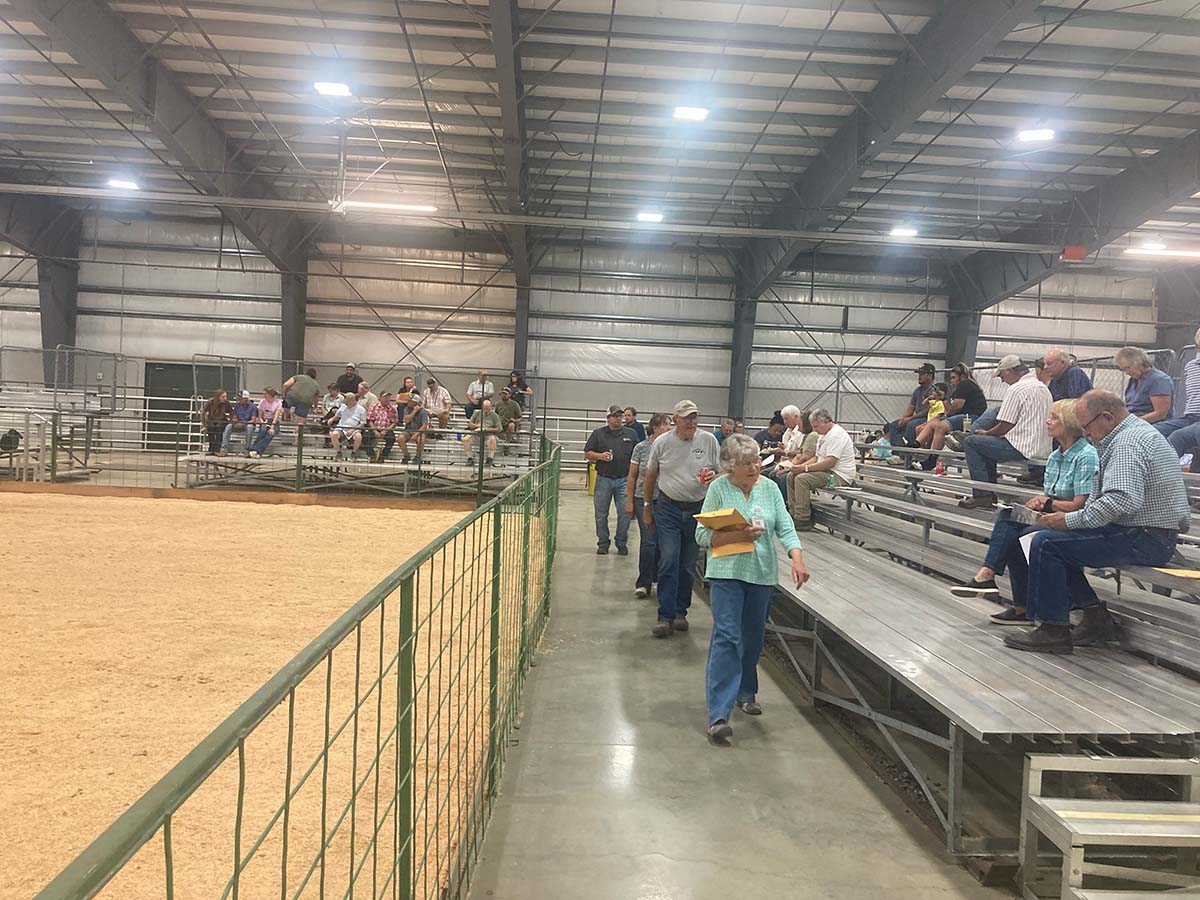 People in a livestock arena with bleachers at a Montana Farmers Union event.